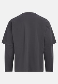 Tricou de culoare gri închis, cu o croială lejeră, decolteu rotund, umeri lăsați și mâneci lungi. Fabricat dintr-un material moale și neted, cu cusături minime.