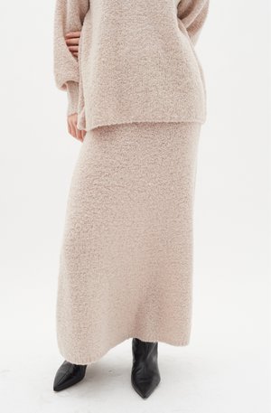Helles Rosa, flauschiges zwei-teiliges Outfit mit einem lockeren Pullover und einem Maxikleid aus weichem Material, ergänzt durch schwarze spitze Stiefeletten.