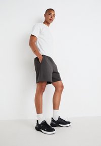 Grå shorts med sidelommer, kombinert med en lys grå t-skjorte og svarte sneakers. Stoffet ser mykt ut, med en avslappet passform.