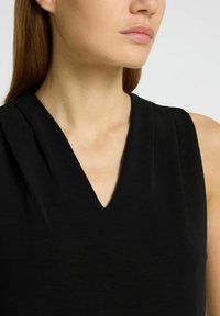 Black sleeveless dress featuring a v-neck, slightly pleated shoulder detail, and smooth texture. Skin tone is neutral.