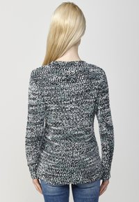 Pulover tricotat gri și negru cu un design texturat. Mâneci lungi și un decolteu rotund. Purtați cu blugi albaștri, fotografiat din spate.