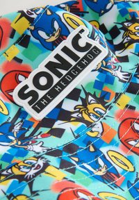 Cap aus buntem Stoff mit Charakteren aus Sonic the Hedgehog. Enthält ein weißes, strukturiertes Logo-Patch mit dem Text "SONIC THE HEDGEHOG".