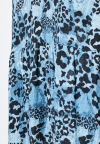 Blaues Tiermustergewebe mit einer Mischung aus schwarzen und dunkelblauen Flecken. Das Material hat eine weiche Textur mit Rüschendetails an der Naht.