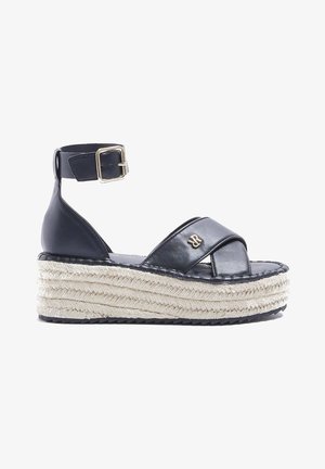Sandales espadrilles en cuir noir avec un épais talon compensé en jute tressé, un design à brides croisées et une boucle à la cheville ajustable.