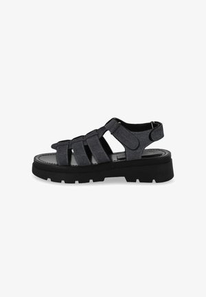 Black denim sandals with multiple crisscross straps, a round toe design, and a chunky black rubber sole featuring tread patterns.