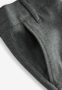 Grå byxor gjorda av texturerad tyg med en slät yta, med platt front, skräddarsydda veck och en ren midjebandsdesign.