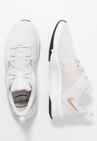 Scarpe da ginnastica bianche con tomaia in mesh, dettagli rosa chiaro e suola intermedia testurizzata. Presentano una punta rotonda e una suola in gomma nera.