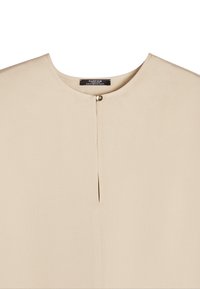 Beżowa bluzka z okrągłym dekoltem, krótkimi rękawami i centralnym detalem w postaci guzika. Tkanina wydaje się gładka z delikatną fakturą. Prosty fason.