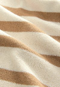 Strickstoff mit abwechselnd breiten Streifen in Beige und Cremefarben, der ein strukturiertes Muster zeigt und eine weiche, flexible Oberfläche hat.