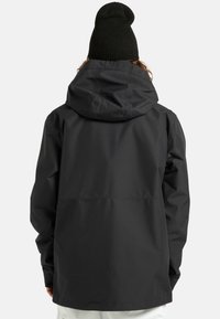 Czarna wodoodporna kurtka z kapturem, o gładkim, matowym wykończeniu i luźnym kroju. Widok z tyłu pokazuje prosty, funkcjonalny design.