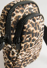 Čierna a hnedá taška s leopardím vzorom, dve zipsové priehradky, textúrovaná tkanina, nastaviteľný popruh a pevné čierne zipsy.