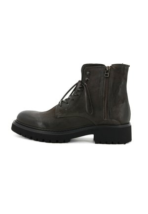 Stivaletto alla caviglia in pelle grigia scura con punta arrotondata, lacci frontali e cerniera laterale. Suola in gomma nera robusta con scanalature profonde per una buona aderenza.