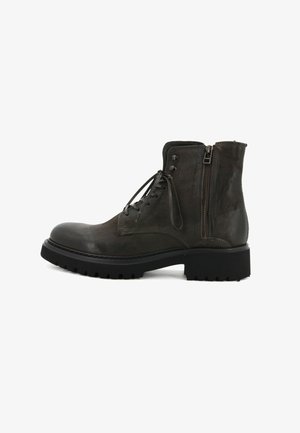 Stivaletto alla caviglia in pelle grigia scura con punta arrotondata, lacci frontali e cerniera laterale. Suola in gomma nera robusta con scanalature profonde per una buona aderenza.