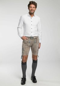 Weißes Langarmhemd mit Knopfleiste und grauen gemusterten Shorts. Die Shorts haben blauer Blumenstickerei und werden mit knielangen grauen Socken und schwarzen Schuhen getragen.