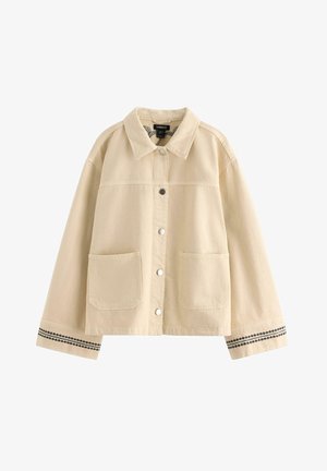 Beige skjortejakke med to forlommer, krave, lange ærmer og sort mønstret kant på ærmekanter.