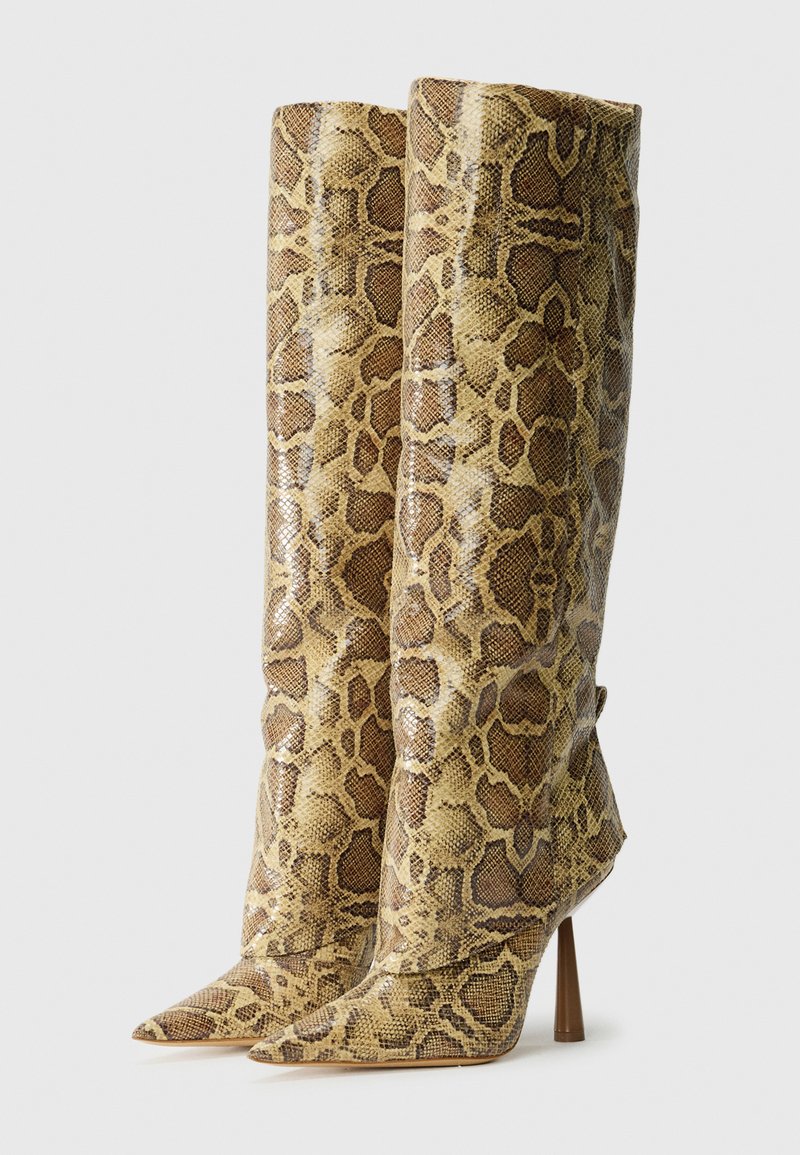 Ein Paar kniehohe Stiefel mit braunem und beigem Schlangenmotif und spitzen Zehen auf hohen zylindrischen Absätzen.