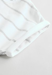 Bela tkanina z belimi horizontalnimi črtami, ki ima rebrast beli ovratnik in manšete, gladko teksturo, zložen na dnu.