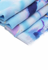 Sciarpa leggera in tonalità di blu e viola, con un motivo ad acquerello e dettagli dorati, e con orli frangiati per una maggiore texture.