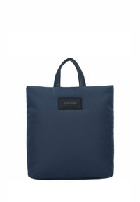Bolso tote azul marino hecho de tela suave, con dos asas resistentes y una etiqueta de logo negra en la parte delantera, de forma cuadrada y diseño minimalista.
