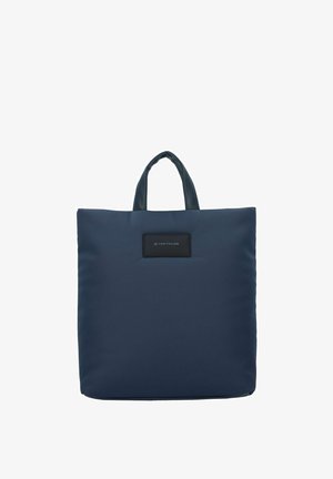 Bolso tote azul marino hecho de tela suave, con dos asas resistentes y una etiqueta de logo negra en la parte delantera, de forma cuadrada y diseño minimalista.
