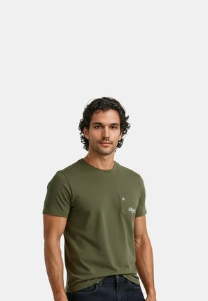 T-shirt vert olive à manches courtes en coton avec un col rond, une poche poitrine et un détail de logo brodé. Texture lisse.