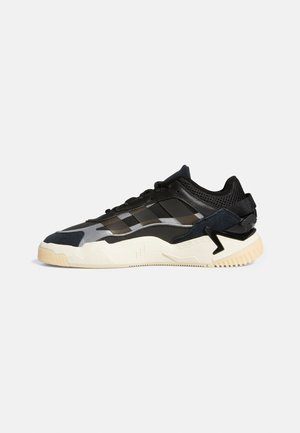 Sneaker atletico nero e grigio con una tomaia in rete testurizzata, suola in gomma e un design angolare. Presenta tre strisce sul lato.