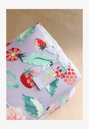 Lavendli värvi kangas punaste maasikate, lillede ja roheliste lehtedega ning õmmeldud Cath Kidstoni kollases kirjas sildiga.