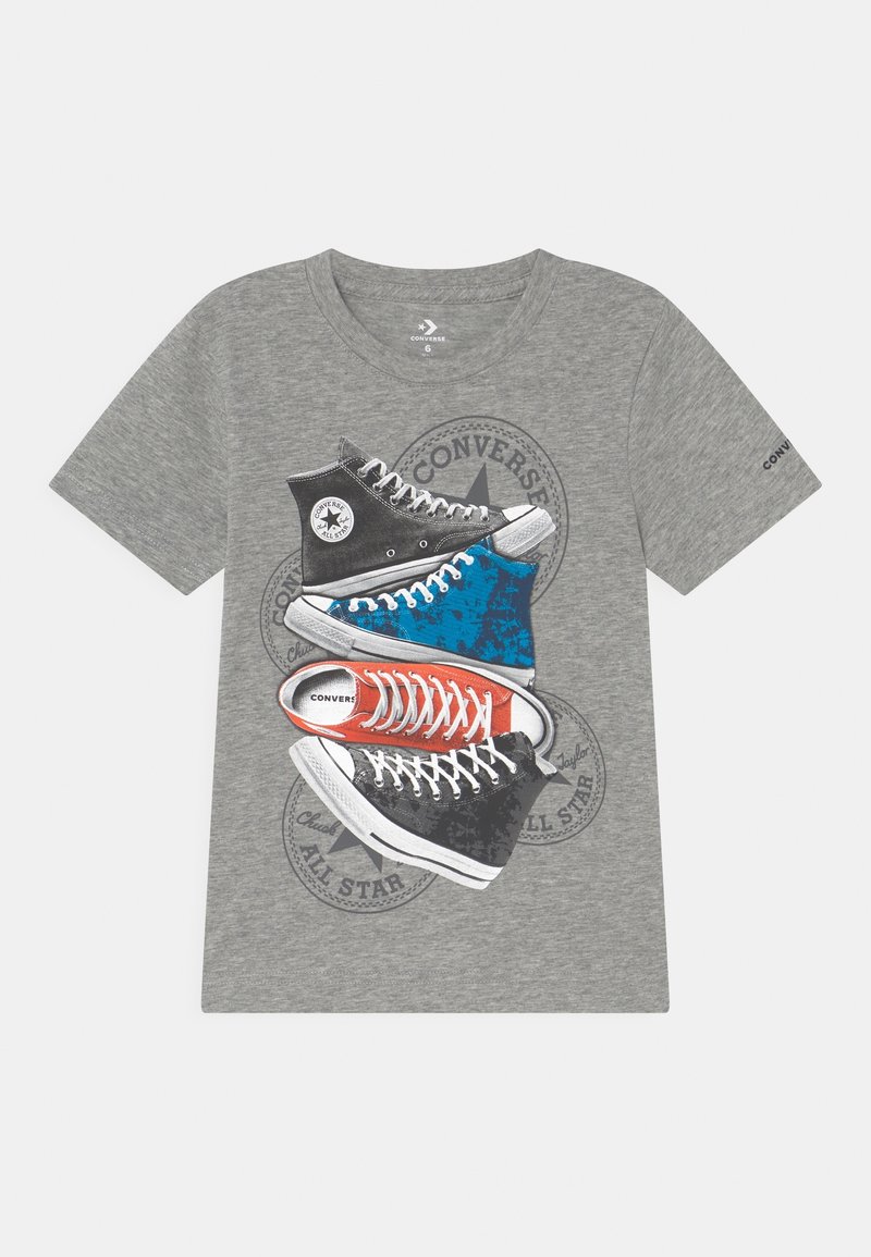 T-shirt gris à manches courtes avec un graphisme représentant quatre baskets Converse All Star empilées en noir, bleu, rouge et noir.