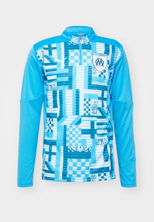 Langarm sportshirt in lichtblauw, met een geometrisch patroon in verschillende tinten blauw, met een ritssluiting aan de hals en een logo op de borst.