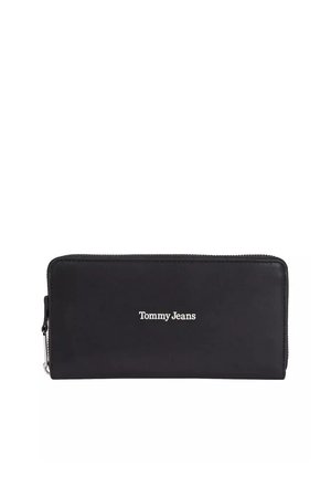 Cartera negra con cremallera y logotipo blanco "Tommy Jeans" centrado en el frente, forma rectangular, textura suave, costuras visibles a lo largo de los bordes.