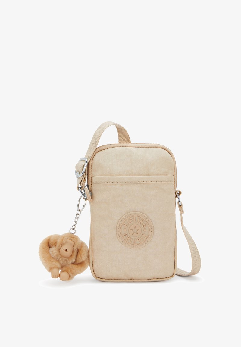 Beige rectangular crossbody bag with Kipling logo patch and a soft plush monkey keychain attached to the strap.