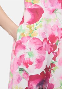 Blumenbedrucktes Kleid mit großen pinken Blumen auf weißem Hintergrund, mit glatter Textur und einer Seitentasche.