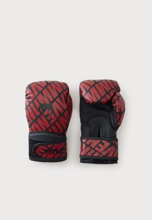 Paire de gants de boxe rouges et noirs avec un motif audacieux et des sangles de poignet ajustables sur un fond blanc uni.
