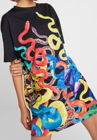 Oversized black t-shirt dress featuring a vibrant, multicolored snake print design with various textures in red, green, blue, yellow, and purple.