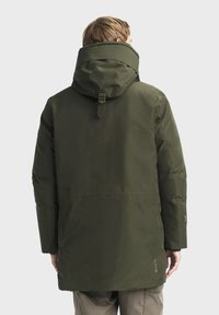 Veste imperméable vert foncé avec un col haut et une capuche ajustable, présentant une coupe droite et un tissu texturé.