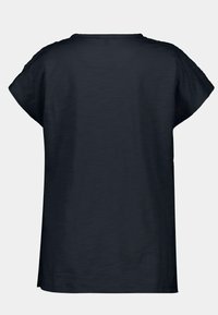 Top negro de manga corta con un ajuste relajado, escote redondo y textura suave. Sin patrones ni acentos visibles. Diseño simple.