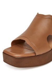 Sandale à plateforme en cuir miel avec bout ouvert, large bride supérieure, et semelle en bois brun foncé.