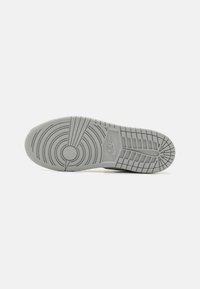 Nike sportcipő talpa világosszürke színben, körkörös és lineáris mintázatokkal, texturált tapadással és középső logó részlettel.