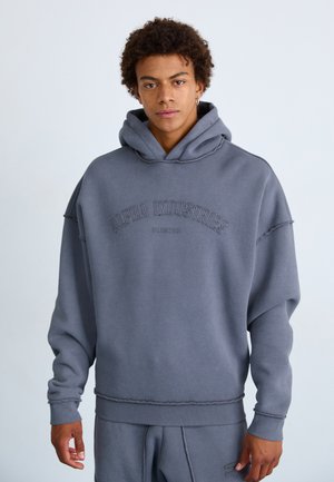Grå hætteSweater med en afslappet pasform. Har "Alpha Industries" broderet i buet tekst hen over brystet. Stoffet har en blød tekstur.