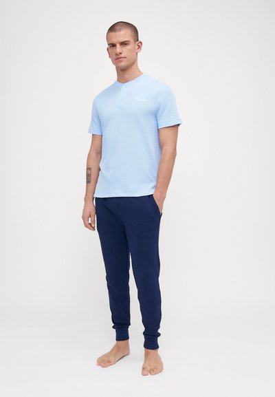 Polo bleu clair à manches courtes avec un motif texturé et une patte de boutonnage à trois boutons, associé à un pantalon de jogging bleu marine avec des poignets côtelés.