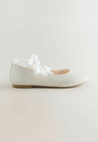 Błyszczący srebrny baletowy balerinek o gładkiej fakturze, zaokrąglonym nosku oraz białej satynowej wstążce z tyłu do zapięcia.