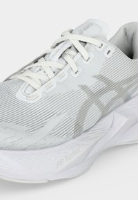 Ανοιχτό γκρι αθλητικό παπούτσι ASICS με λευκά κορδόνια, υφασμένο πλεκτό επάνω μέρος και μαξιλαρωμένη σόλα με την ένδειξη "FF Turbo".