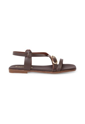 Brun flad sandal med ankelrem, tårem og guldbeslag i siden, vist mod en hvid baggrund.