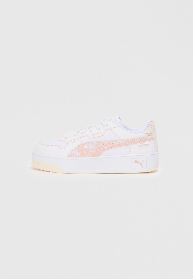 Zapatilla blanca con un panel texturizado rosa y acentos brillantes. Presenta una suela blanca gruesa y un diseño de cordones. Logo de Puma visible en el lateral.