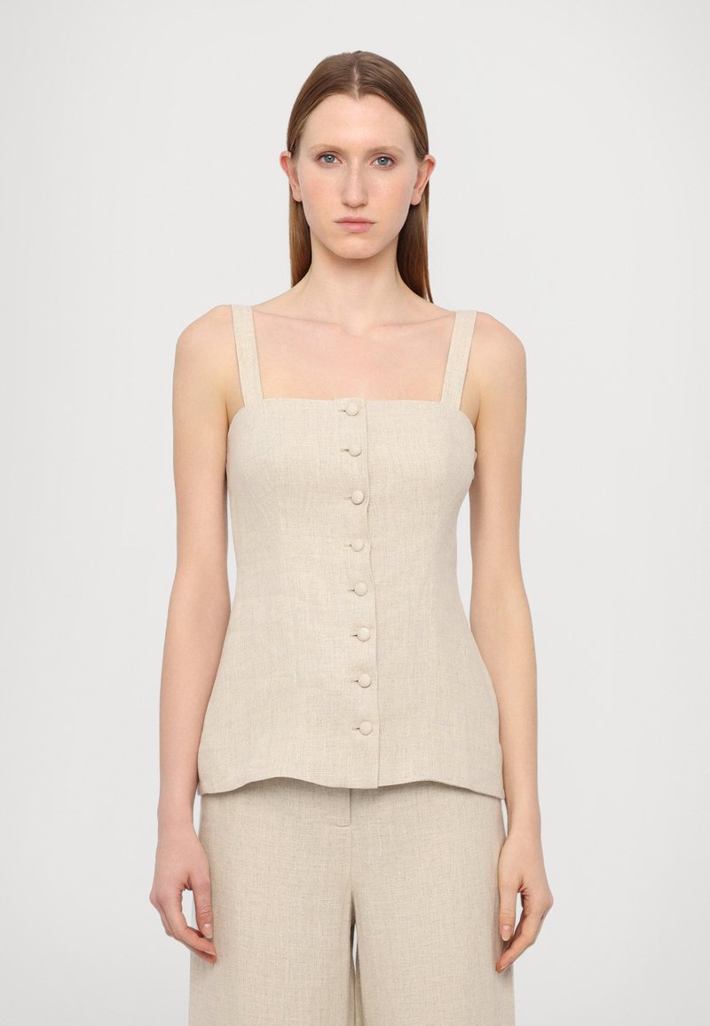 Beige linnen tanktopp med firkantet hals, brede stropper og frontknapper. Kombinert med matchende lyse beige bukser.