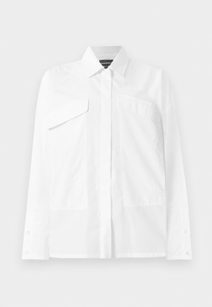 White button-up shirt featuring a classic collar, two chest pockets, and long sleeves with cuff buttons. Smooth fabric with minimal texture.