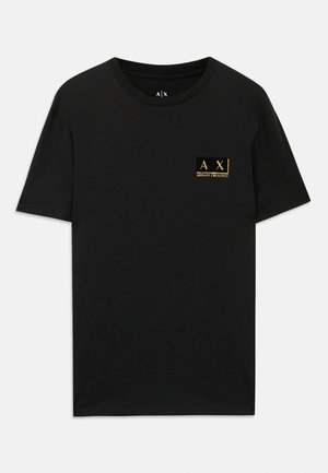 Camisa de algodón negra con cuello redondo. Presenta un pequeño parche de logo dorado en el lado izquierdo del pecho con el texto "AX Armani Exchange". Corte clásico.