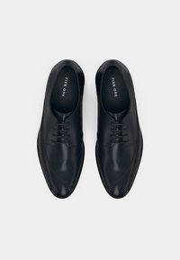 Pair of black leather lace-up dress shoes with pointed toes and branded insoles on a white background.