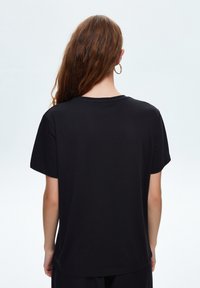 Czarny t-shirt z krótkimi rękawami, okrągłym dekoltem, gładką fakturą i prostym krojem, bez widocznych wzorów ani zdobień.