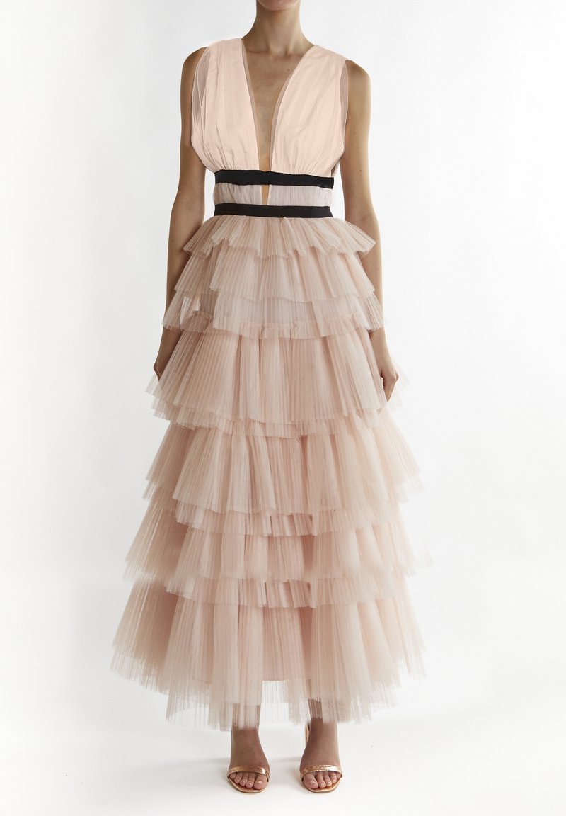 Abito rosa chiaro con scollatura a V profonda, cintura nera e gonna in tulle a strati con volant e texture trasparente.